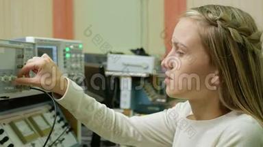 年轻的女工程师学生在实验室用电气仪器工作。 她小心翼翼地转动车轮时钟